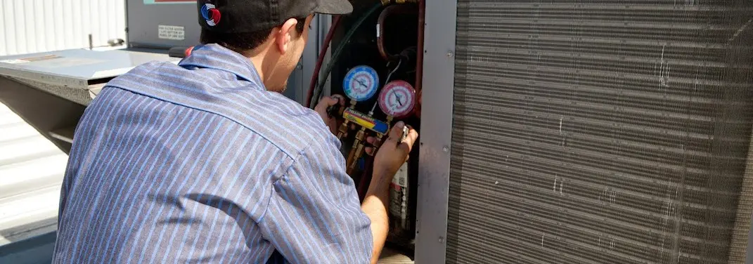 HVAC technician servicing a condenser unit in Mills River